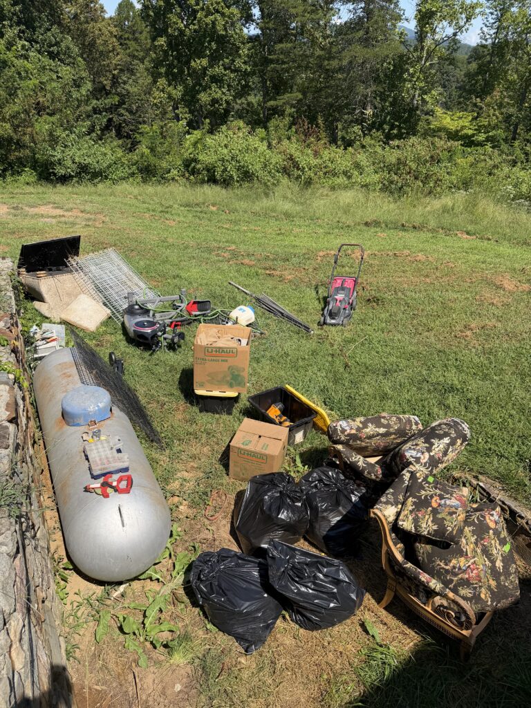 Before yard junk removal in Blairsville, Georgia, showing unwanted furniture, trash bags, boxes, metal items, and miscellaneous equipment awaiting removal by Appalachian Junk Removal, LLC.