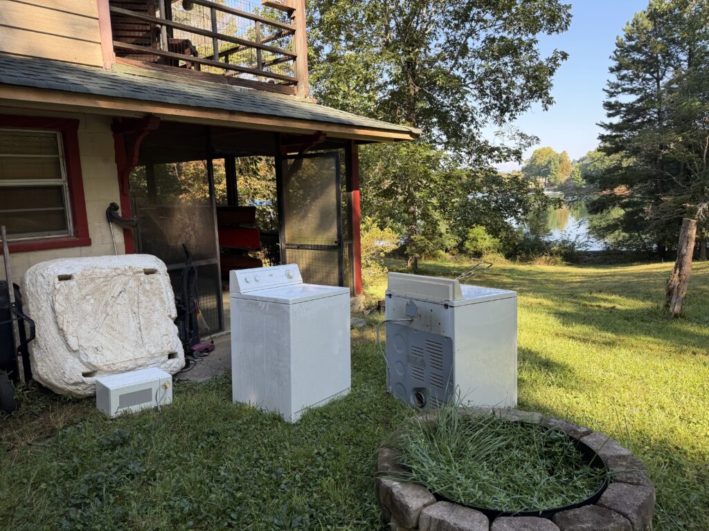 BEFORE — Washer, dryer, microwave, and miscellaneous items awaiting removal beside a screened porch in Hiawassee, Georgia, by Appalachian Junk Removal, LLC.