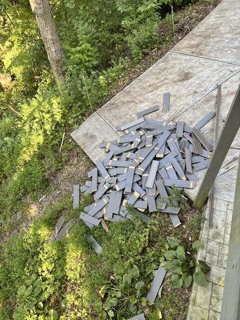 BEFORE — Pile of composite decking cutoffs beside a concrete walkway awaiting removal by Appalachian Junk Removal, LLC in Hiawassee, Georgia.