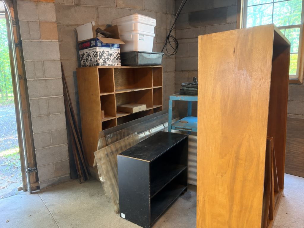 Before garage junk removal in Tiger, Georgia, showing shelving, bookcases, storage containers, and miscellaneous items awaiting removal by Appalachian Junk Removal, LLC.
